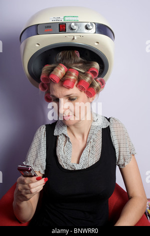 Femme textos sur téléphone mobile tout en hairdressers Banque D'Images