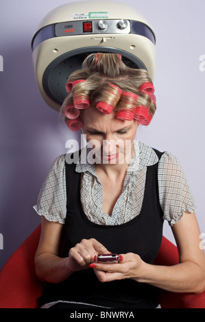 Femme textos sur téléphone mobile tout en hairdressers Banque D'Images