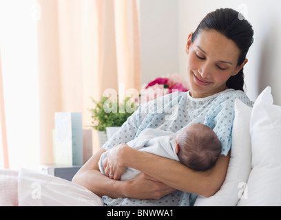 Mother holding newborn baby in hospital bed
