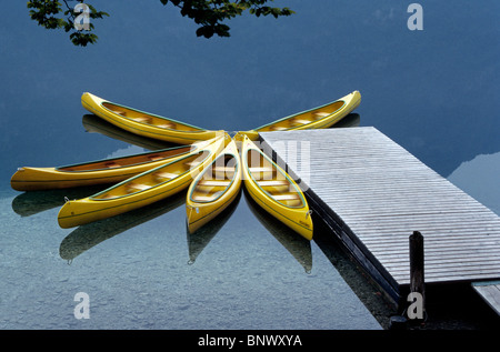 Six canots jaunes vacanciers attendent à un quai sur le lac de Bohinj calme, le plus grand lac glaciaire dans les Alpes Juliennes en République de Slovénie, de l'Europe. Banque D'Images