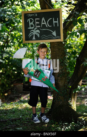Première journée à l'école. Garçon avec cône en carton dans la cour de l'école. Banque D'Images