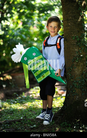 Première journée à l'école. Garçon avec cône en carton dans la cour de l'école. Banque D'Images