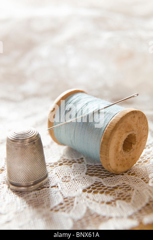 Bobine de coton vintage avec aiguille et dé d'argent dentelle blanche sur Banque D'Images