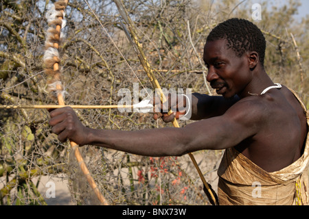 Hadza man practicing archery, Tanzanie Banque D'Images