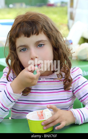 Brunette little girl eating ice cream d'été cuillère couleur Banque D'Images