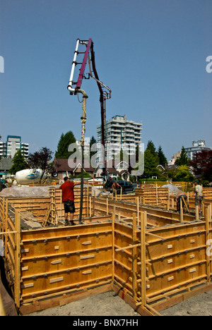 Camion-pompe béton utilise très grands tuyau de flèche hydraulique pour atteindre les formes de fondation de contreplaqué à Vancouver house construction site Banque D'Images
