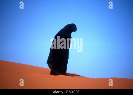 Femme en prière musulmane sur une dune de sable en Arabie Saoudite Banque D'Images