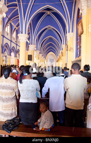 Des fidèles dans la Cathédrale Catholique Antsirabe, Madagascar, au cours de la messe du dimanche matin. Un enfant est à l'arrière. Banque D'Images