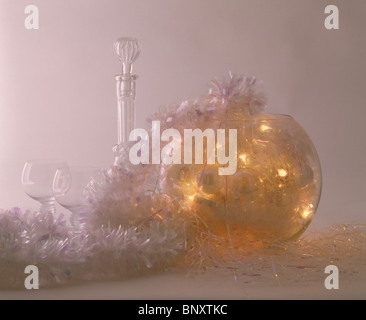 Close-up of Christmas baubles et lumières en globe de verre à côté de la carafe en verre et d'argent clinquant garland Banque D'Images