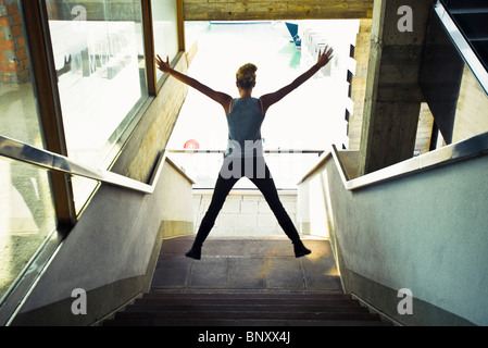 Adolescente en escalier, sauter dans l'air, vue arrière Banque D'Images