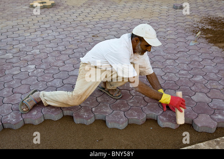 L'installation de pavés imbriqués l'homme sur le sol pour créer de trottoir, Ouled Berhil, Maroc Banque D'Images