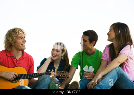 Les jeunes amis, l'un jouant de la guitare acoustique Banque D'Images