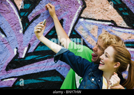 Jeune couple photographing themselves with cell phone Banque D'Images