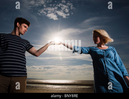 Couple on beach holding soleil dans les mains Banque D'Images