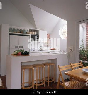 Tabourets en bois encastré dans l'espace de stockage dans les bar de petit-déjeuner dans la salle à manger cuisine moderne blanc Banque D'Images