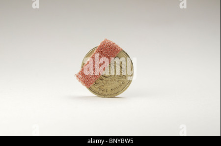 Une livre de monnaie avec petit plâtre sur fond blanc. Banque D'Images