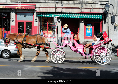 Deux touristes profitant d'une randonnée en buggy tiré par des chevaux dans les rues du Vieux Montréal Banque D'Images