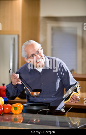 Senior Hispanic man cooking at home in kitchen Banque D'Images