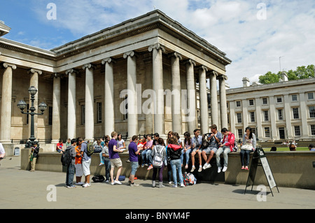 Les jeunes gens assis sur le mur extérieur de la British Museum Bloomsbury London Borough of Camden England UK Banque D'Images