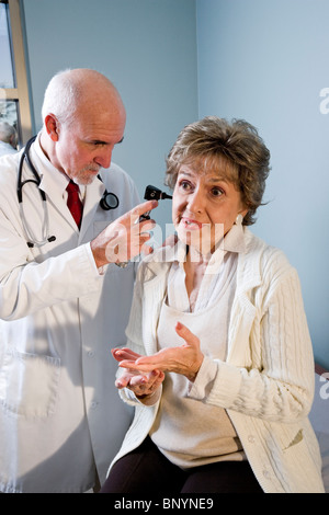 Doctor examining senior woman looking in ear Banque D'Images