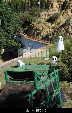 Troglodytisme et cheminées avec des machines agricoles dans l'avant-plan, Guadix, Province de Grenade, Andalousie, Espagne, Europe de l'Ouest. Banque D'Images