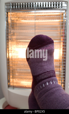 Pieds de réchauffement portant une paire de chaussettes de laine en face d'un radiateur électrique Banque D'Images