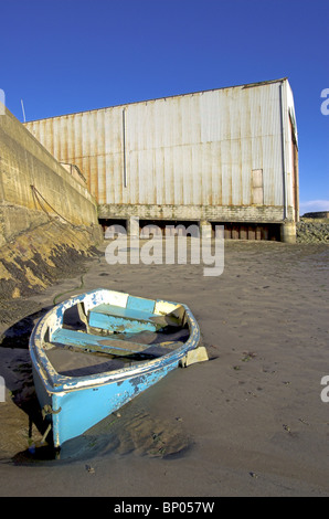 Un petit bateau coincé dans la boue à St Monans Harbour, Fife, avec Miller boatyard dans l'arrière-plan Banque D'Images