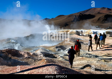 Les touristes au milieu des piscines de boue bouillante au sol de Manana Geyser Basin en Bolivie. Banque D'Images