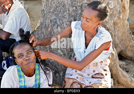 Négociant marché femme ayant les cheveux tressés par un collègue à Toliara Tuléar fka Toliary aka, Atsimo Andrefana, sud est de Madagascar Banque D'Images