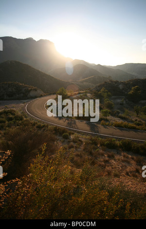 Courbant virage de la route dans la région montagneuse près de Murcie, Espagne du sud, avec des reflets - le tournage dans le soleil Banque D'Images