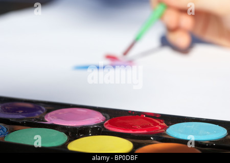 Les peintures à l'aquarelle est utilisé par un enfant à peindre sur papier Banque D'Images