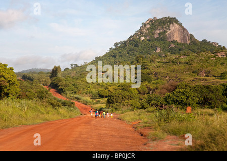 Le Mozambique, près de Nampula. Les enfants marcher dans la route de terre rouge vif à l'école. Banque D'Images