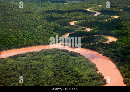 Le Pérou. Les eaux rouges d'un important affluent de la Madre de Dios river wind par jungle épaisse près de Puerto Maldonado. Banque D'Images