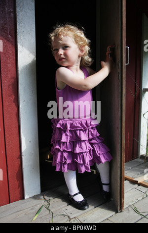 Petite fille vêtements enfant en partie à l'extérieur de l'ouverture d'un modèle de porte en bois playhouse publié Banque D'Images