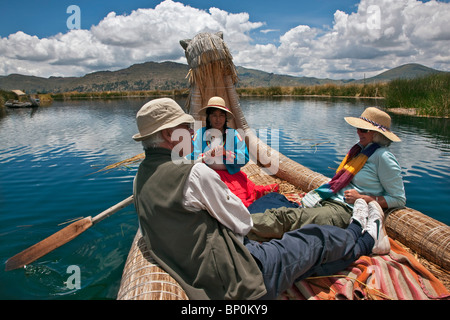 Le Pérou, les touristes étant ramé dans un bateau de roseau autour des îles flottantes uniques d'Uros sur le lac Titicaca. Banque D'Images