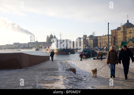 La Russie, Saint-Pétersbourg ; un couple en train de marcher avec un chien le long de la rivière Neva embarquement en hiver Banque D'Images