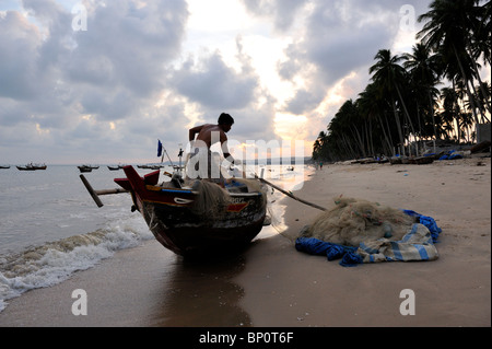 Filets de chargement pêcheur sur son bateau. Mui Ne, Vietnam Banque D'Images