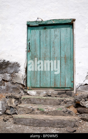 Vieille porte en bois espagnol bleu dans un mur blanc avec des marches en pierre Banque D'Images