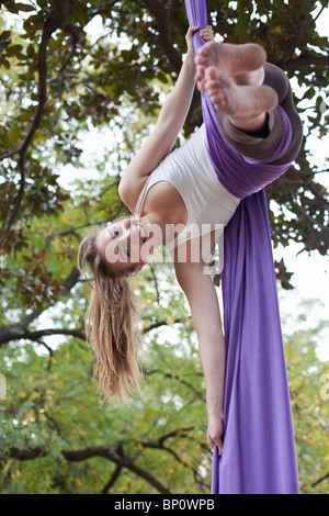 Jeune femme faisant des acrobaties dans l'arbre Banque D'Images