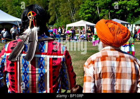 Un indigène en costume traditionnel et un Sikh portant un turban regarder le concours de danse traditionnelle au pow-wow de Wendake Banque D'Images