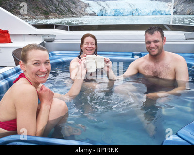 Aventure-Trois voyageurs d'affaires bénéficient d'un café bien chaud, et vous détendre dans un bain à remous tout en passant par un glacier froid, le passage de l'Intérieur, de l'Alaska. Banque D'Images