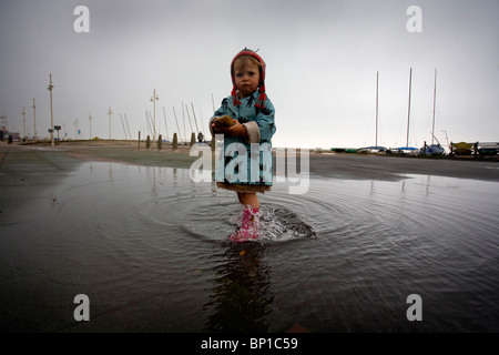 Une petite fille joue dans une flaque d'eau sur le front de mer de Brighton. Photo par James Boardman. Banque D'Images