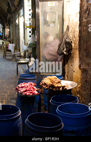 L'Alep souk ancien marché, boucheries vendant de l'agneau et du boeuf halal sur la rue, les agneaux pieds s'asseoir sur le seau Banque D'Images