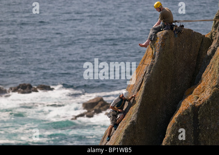 Les grimpeurs sur des rochers sur la côte de Gwennap Head à Cornwall. Banque D'Images