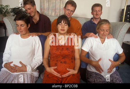 Les femmes enceintes en consultations prénatales une classe avec leurs maris ou partenaires de masser les épaules Banque D'Images