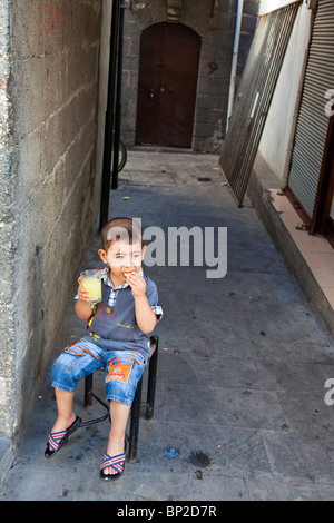 Jeune garçon manger dans la vieille ville de Diyarbakir, est de la Turquie Banque D'Images