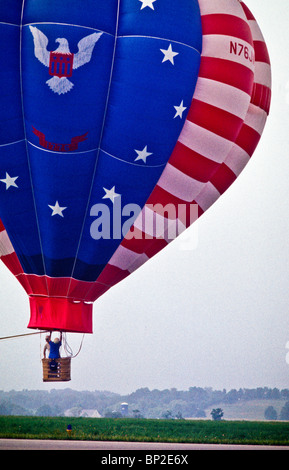 Hot Air Balloon riders soar , flotter au-dessus des champs de ferme de Lancaster, tôt le matin. Banque D'Images