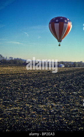 Hot Air Balloon riders soar , flotter au-dessus des champs de ferme de Lancaster, tôt le matin. Banque D'Images