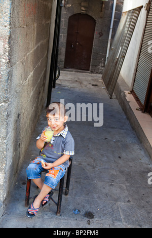 Jeune garçon manger dans la vieille ville de Diyarbakir, est de la Turquie Banque D'Images