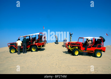 Les voiturettes de dunes avec les touristes sur le vaste désert de dunes de sable près de l'Oasis de Huacachina, Ica, Pérou. Banque D'Images